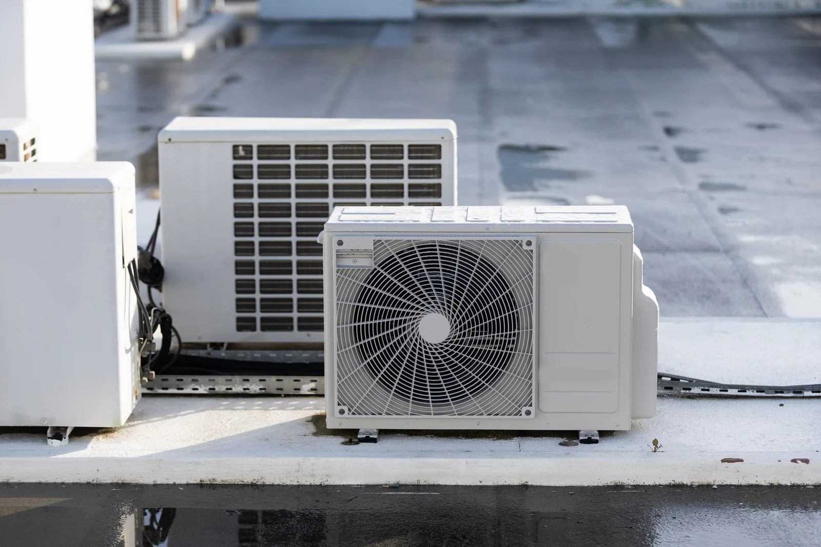 Outdoor condensing units standing on a wet flat roof deck — HVAC contractor insurance in Iowa.
