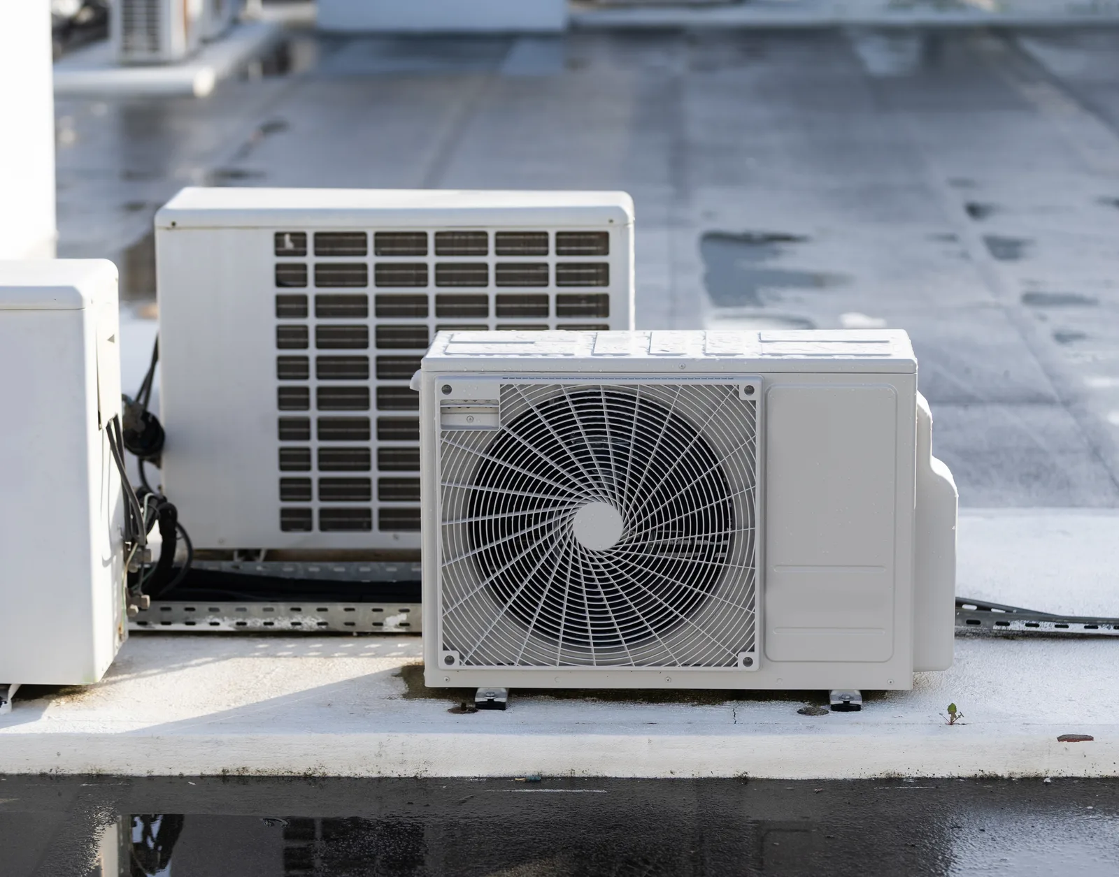 A pair of outdoor condensing units on a flat roof deck after rain — HVAC contractor insurance in Virginia.