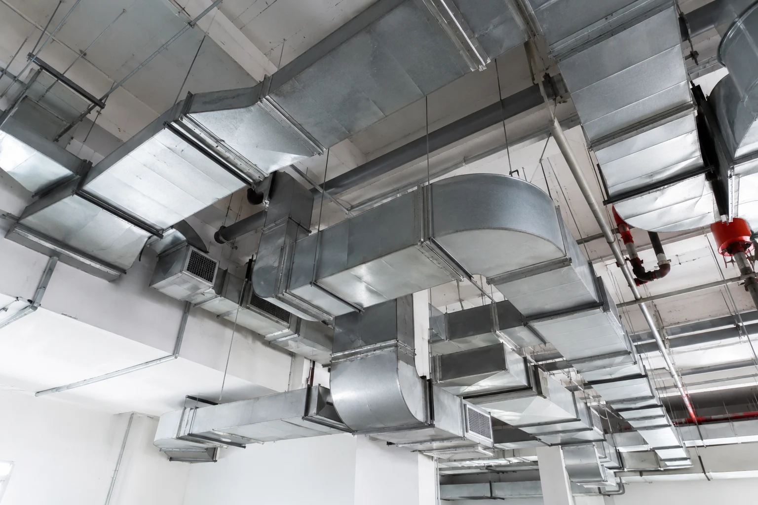 Galvanized sheet-metal ductwork running across a commercial ceiling — HVAC contractor insurance in Maine.