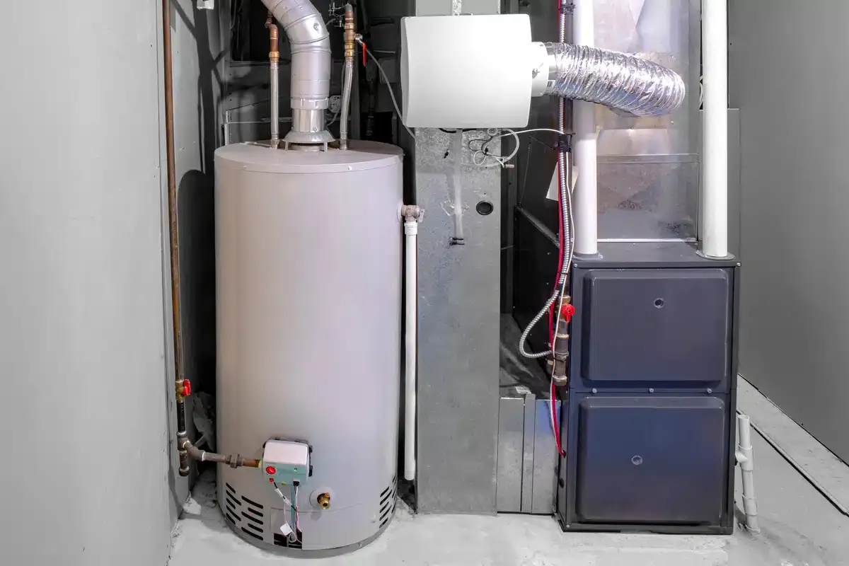 A residential gas furnace and water heater with flue venting in a utility space.