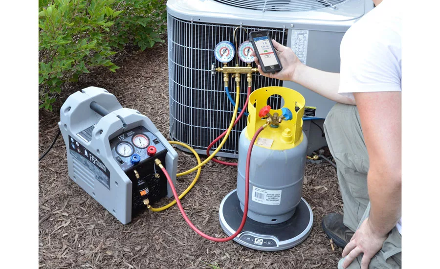 A refrigerant recovery machine and gauge manifold set up beside a condenser unit.