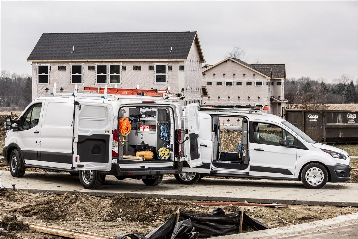 Two HVAC work vans with open equipment racks parked at a jobsite.
