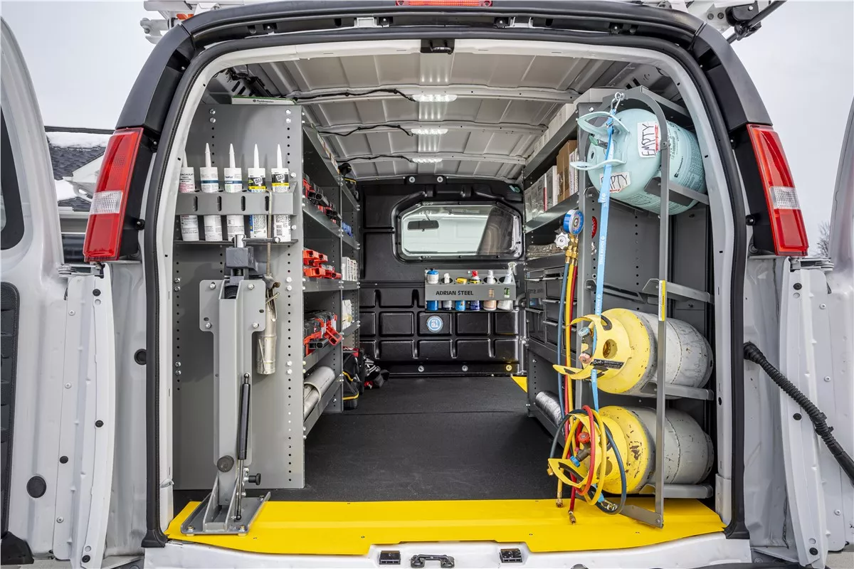 The equipped interior of an HVAC service van with racked tools and refrigerant cylinders.